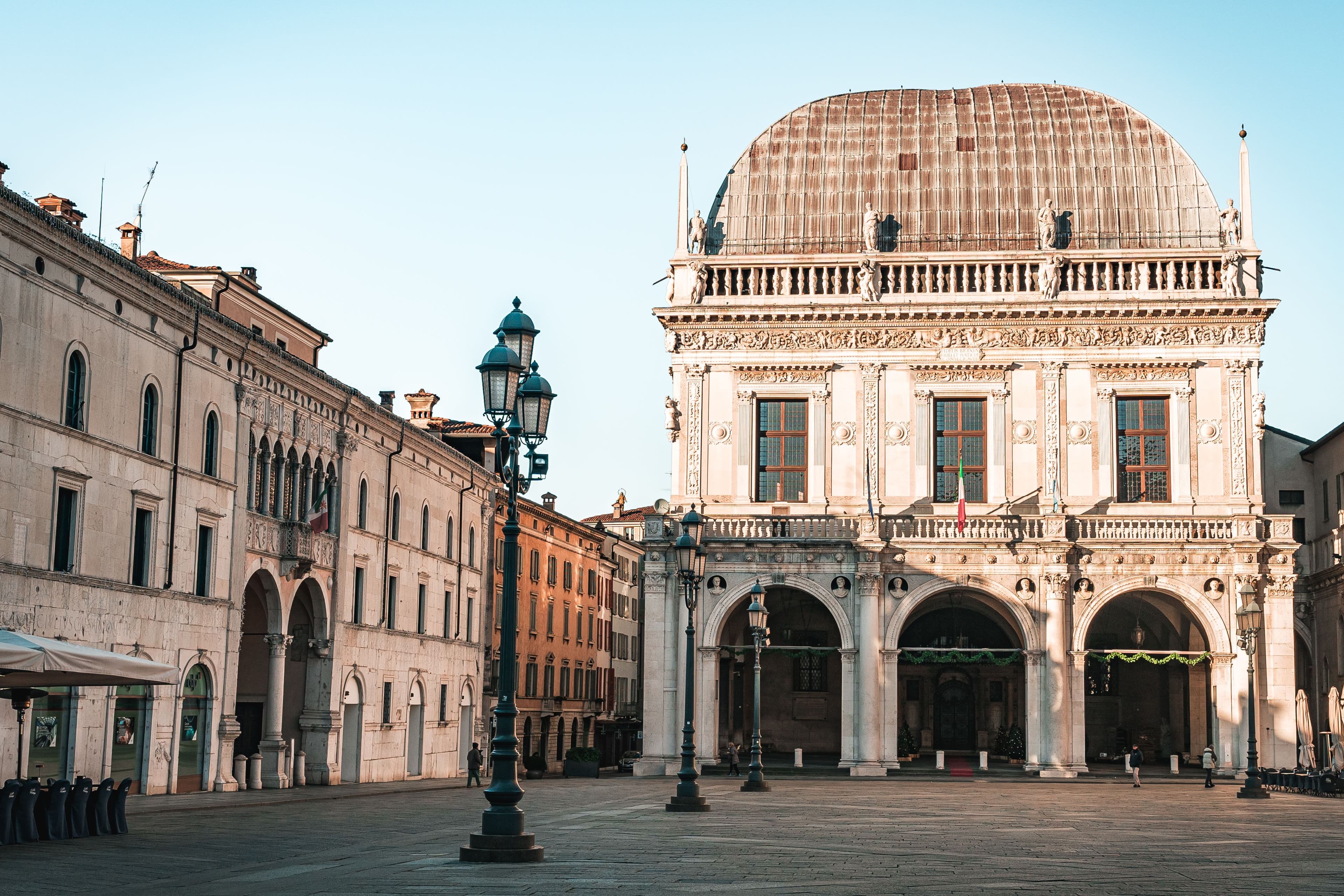 The Palazzo della Loggia in Piazza della Loggia, Brescia, with its domed lead roof, arcaded ground floor and cast-iron lamp posts in early morning light