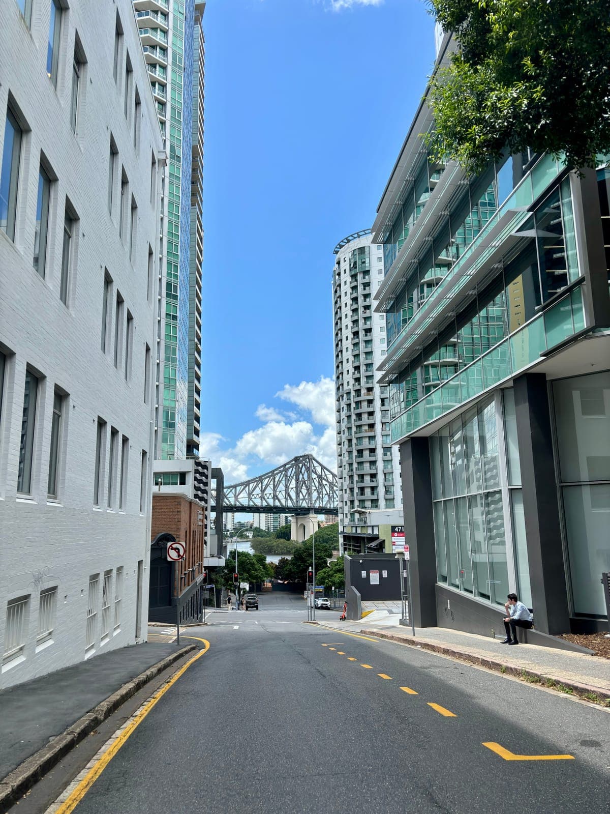 The steel truss of the Story Bridge framed between towers at the end of a Brisbane street; the bridge is closed to traffic for the 2027 marathon