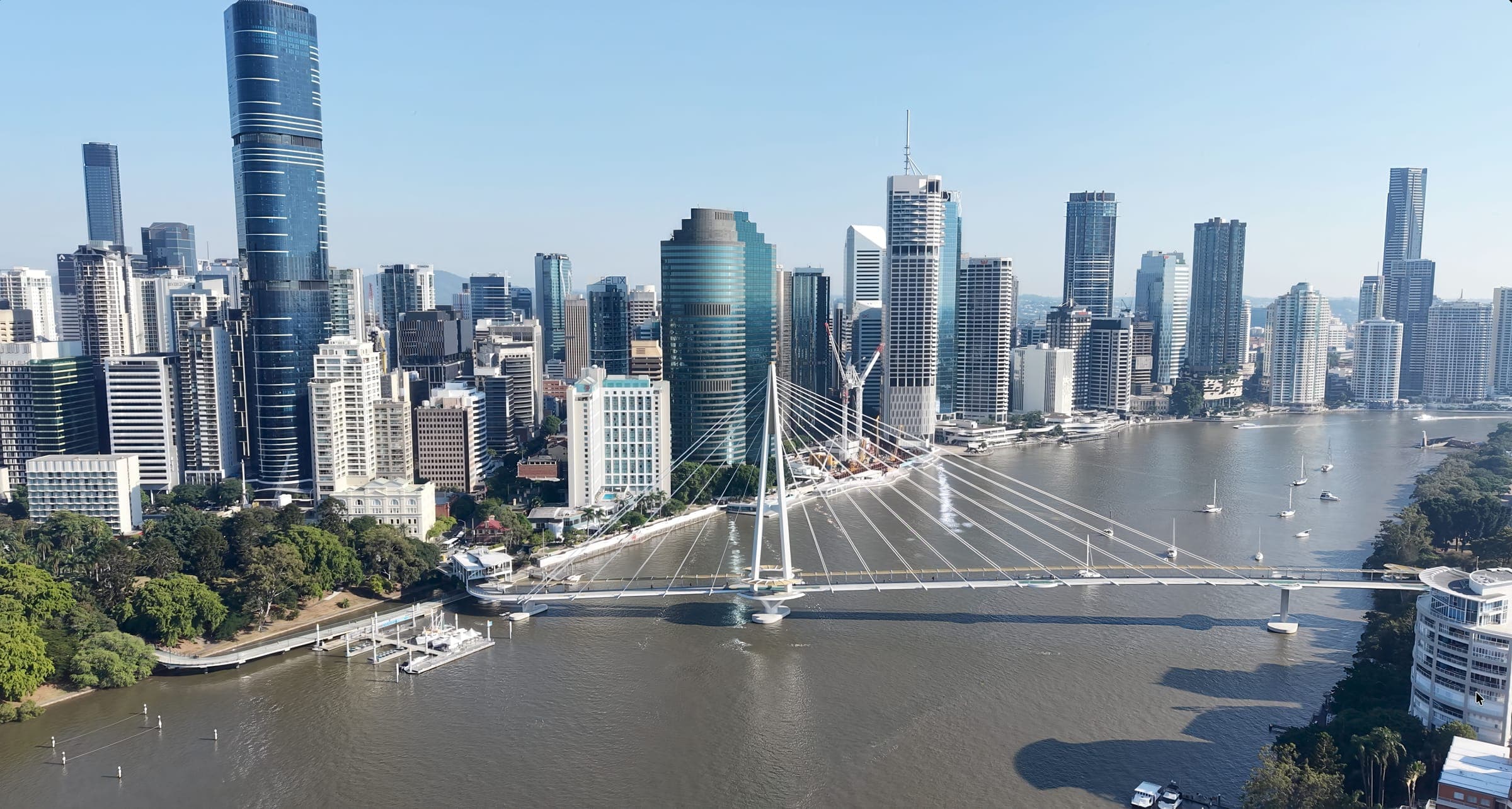 The Brisbane CBD skyline above the Brisbane River, with the white cable-stayed Kangaroo Point pedestrian bridge crossing towards the City Botanic Gardens, where the Brisbane Marathon finishes