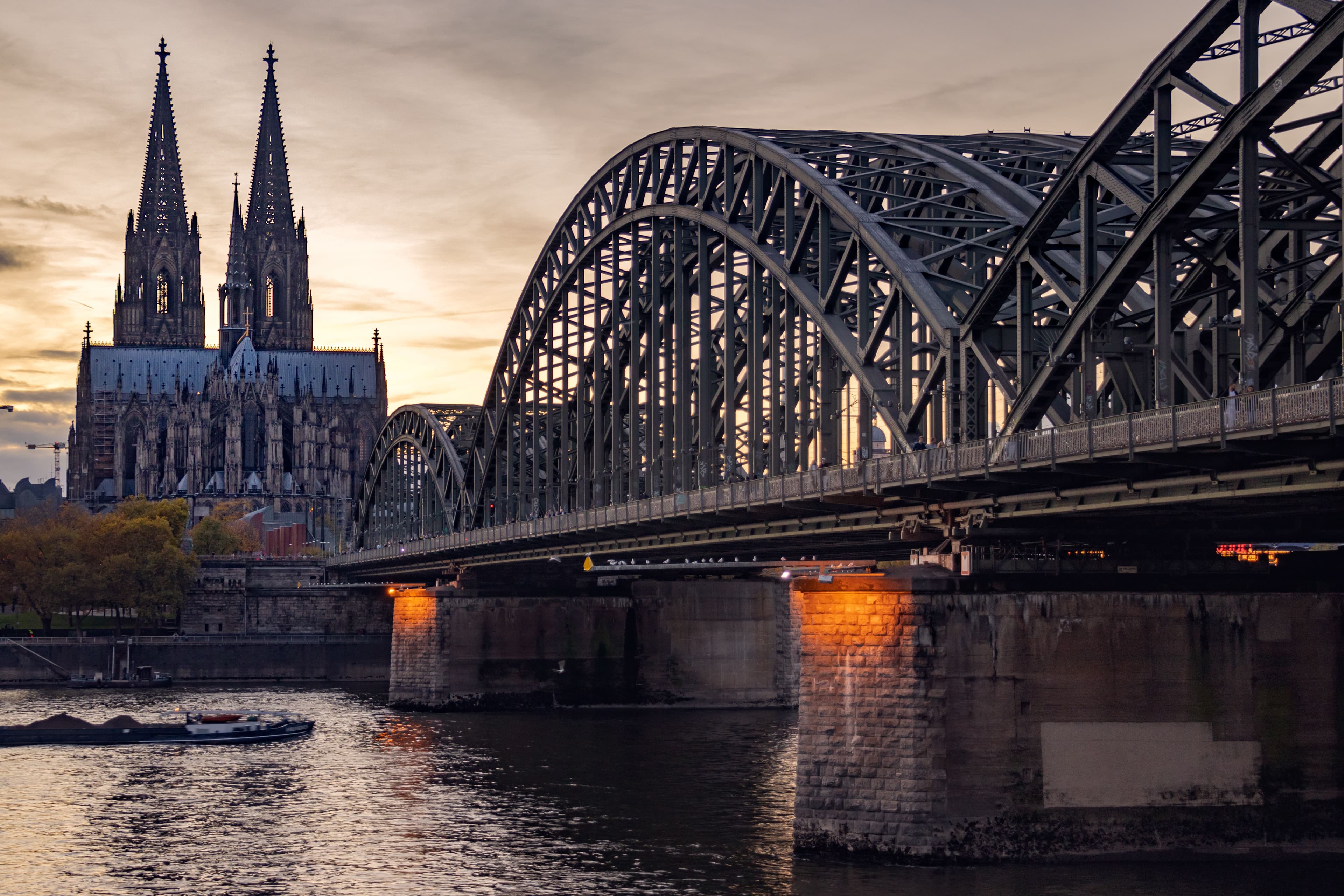 The Hohenzollern Bridge crossing the Rhine at sunset with Cologne Cathedral's twin spires behind it, on the marathon's opening kilometre