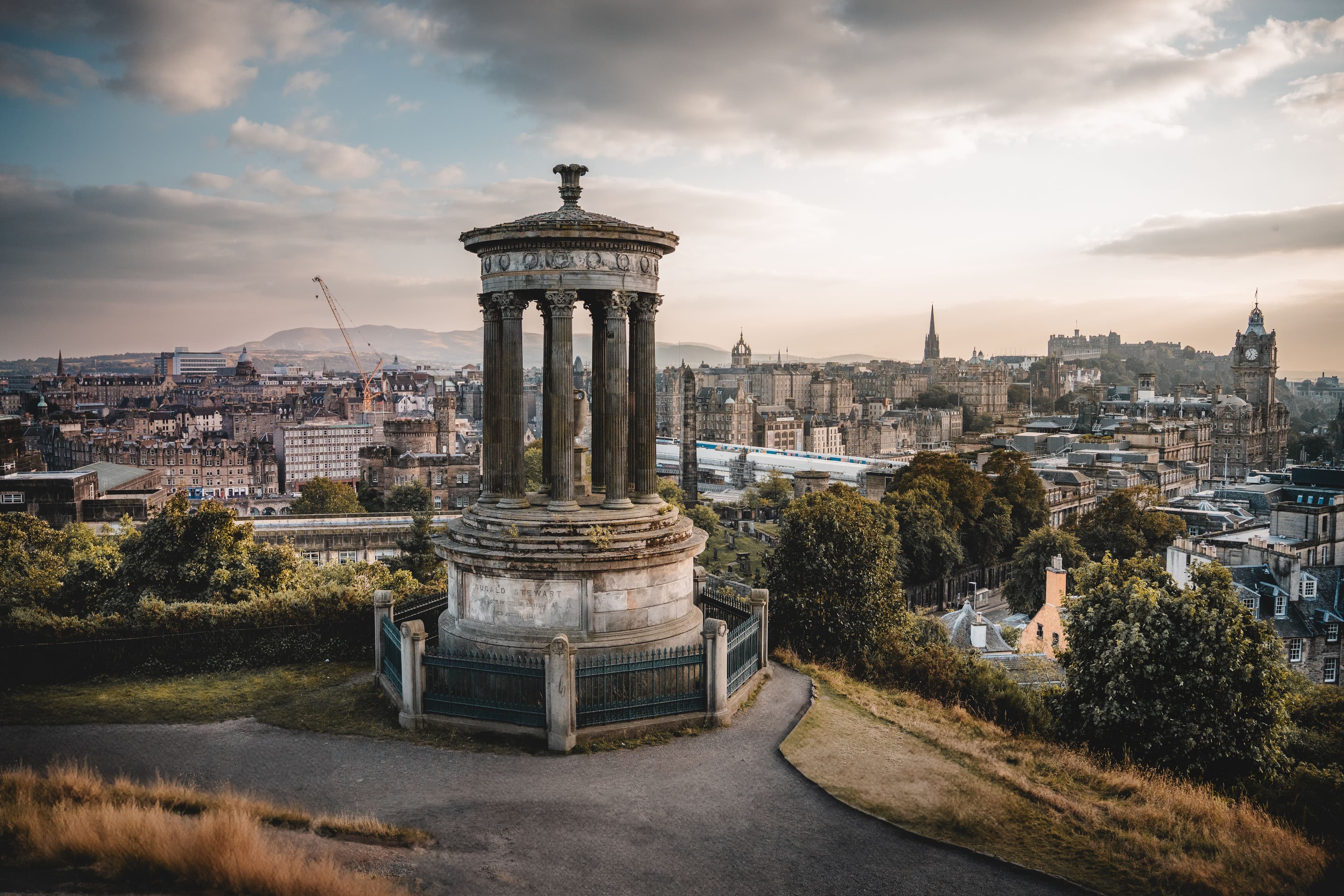 The Dugald Stewart Monument on Calton Hill above the Edinburgh skyline, with the Balmoral clock tower and Edinburgh Castle visible in the distance