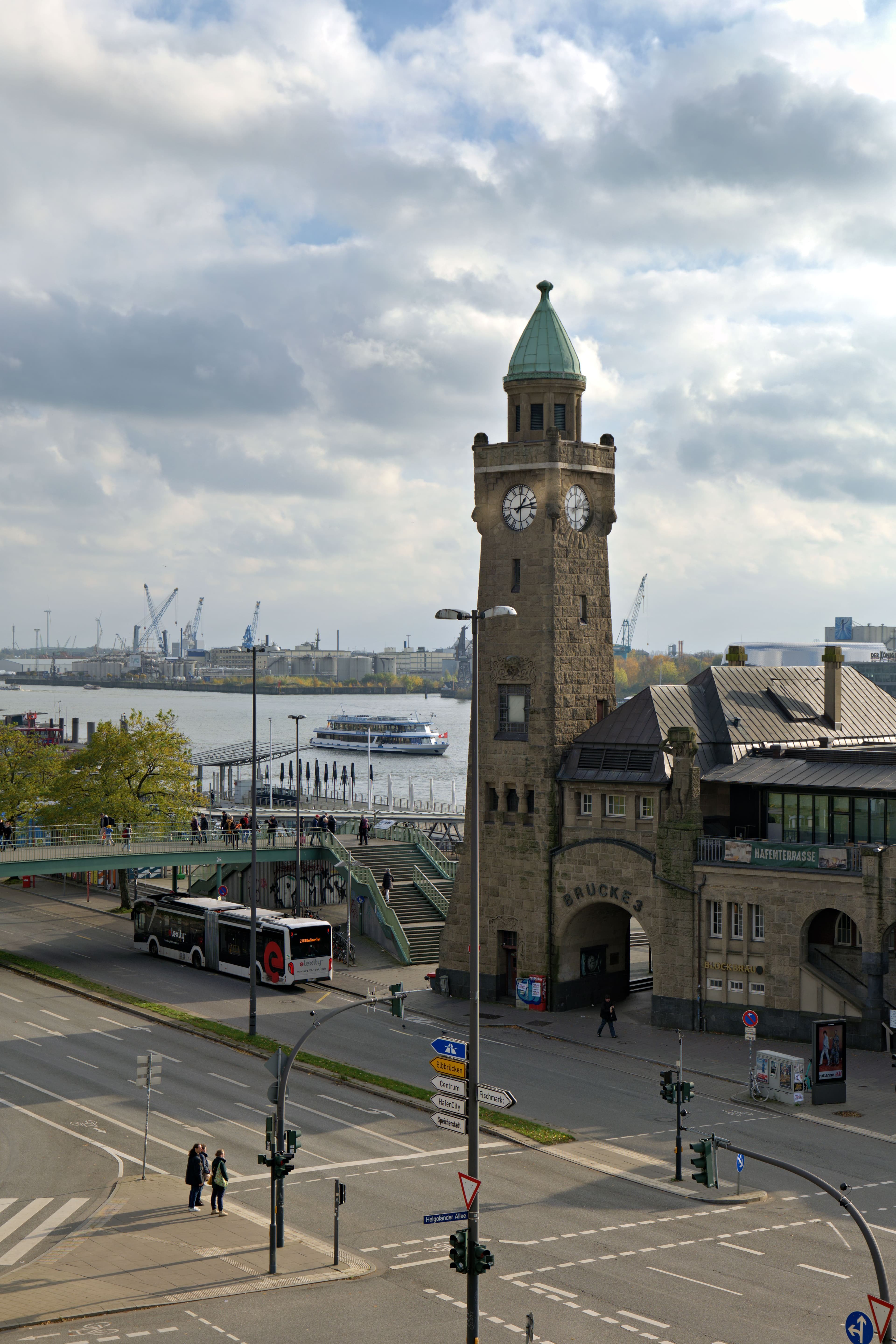The clock tower at St Pauli Landungsbrucken overlooking the Elbe harbour, with a passenger ferry passing below