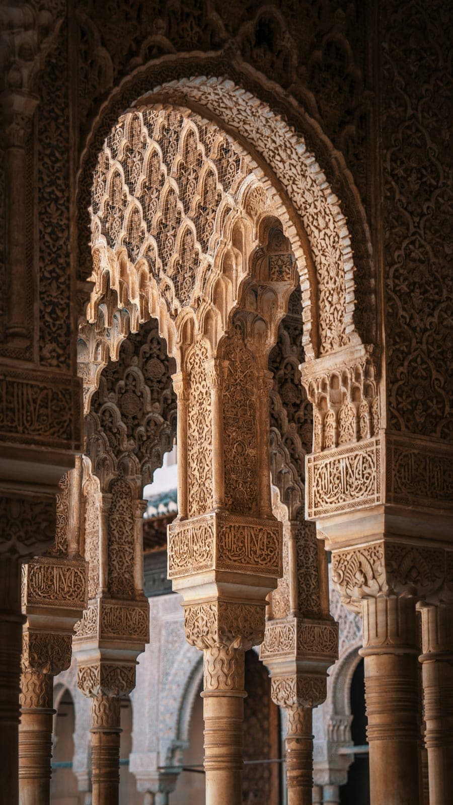 Carved stucco arches and slender marble columns in the Nasrid Palaces of the Alhambra in Granada
