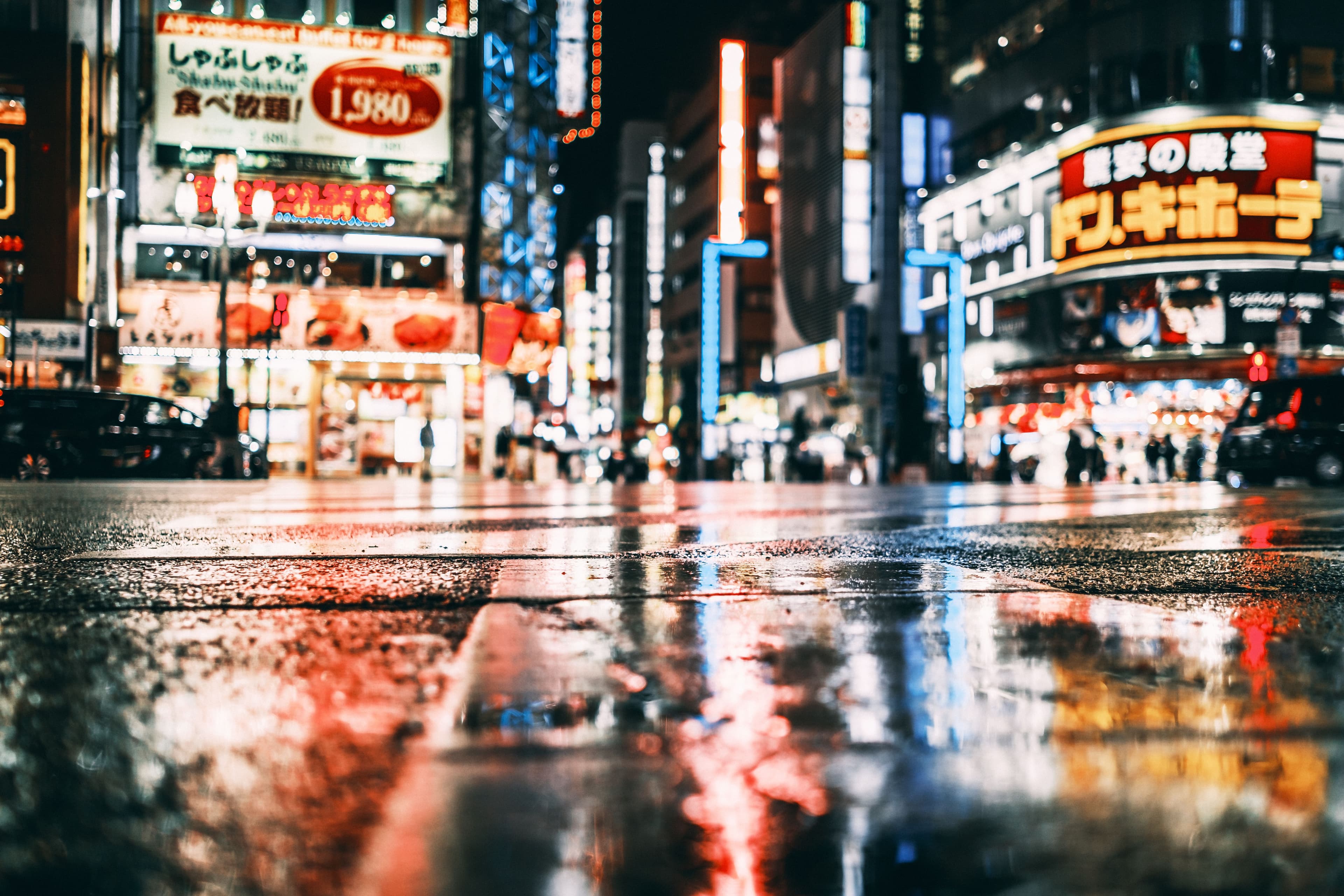 Neon-lit street in Tokyo at night, reflecting on wet pavement - the city's character in the districts near the marathon finish