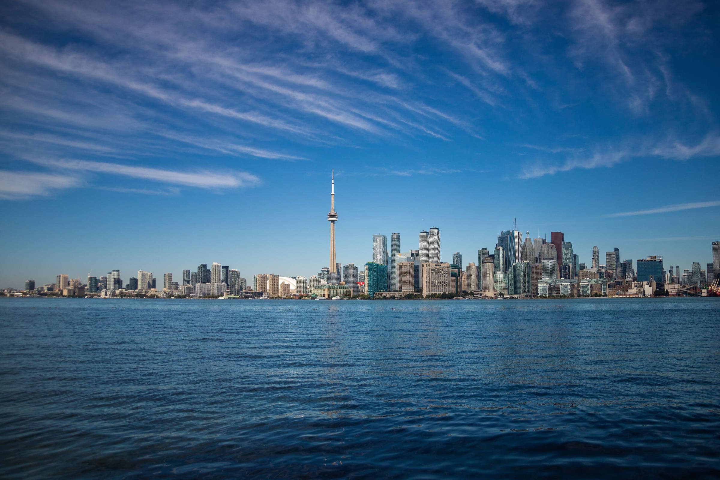 The Toronto skyline from across Lake Ontario on a clear autumn day, with the CN Tower at the centre and the downtown towers either side. The marathon runs along this waterfront and finishes in the downtown core.