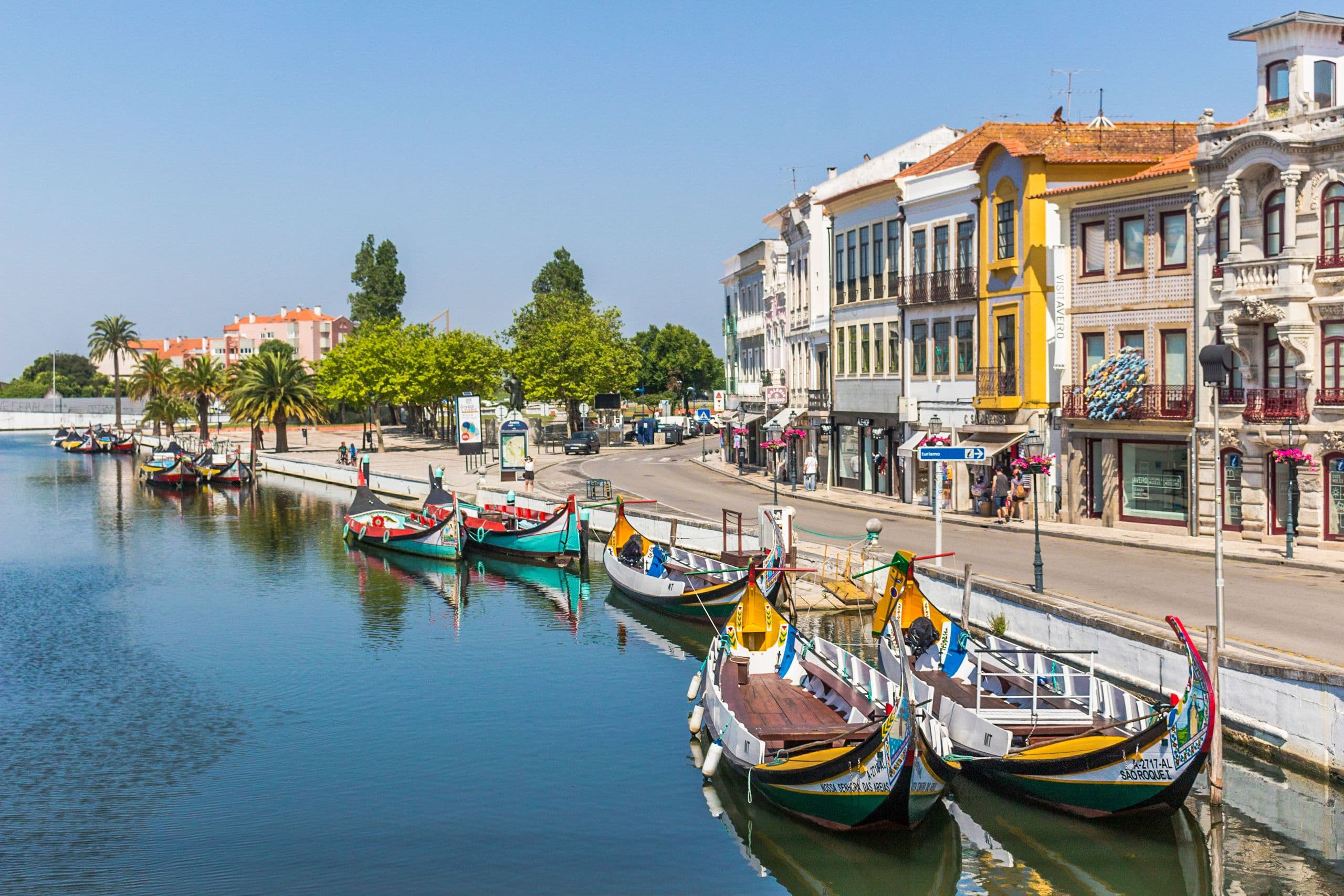 Moliceiro boats with painted prows moored on the Canal Central in Aveiro, below the tiled and Art Nouveau frontages of the city centre about a kilometre from the marathon start at Cais da Fonte Nova