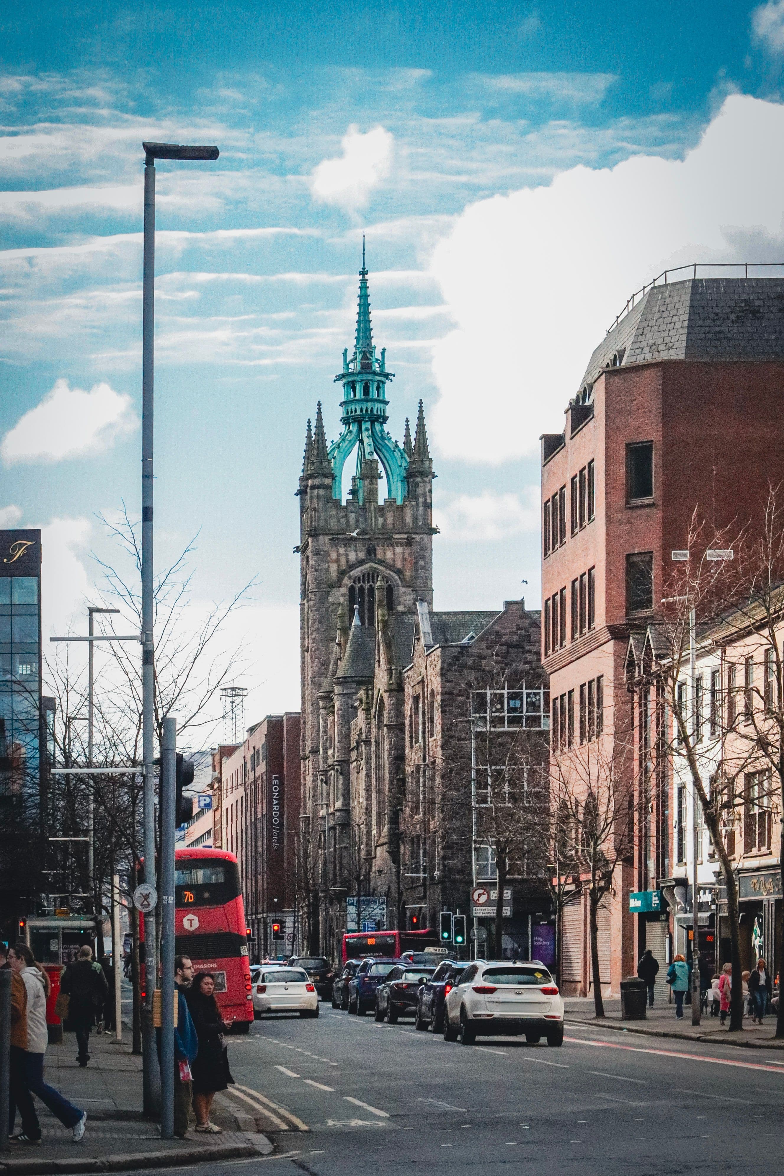 A Cathedral Quarter street in Belfast city centre, with a Gothic church spire, near hotels recommended for the Belfast City Marathon