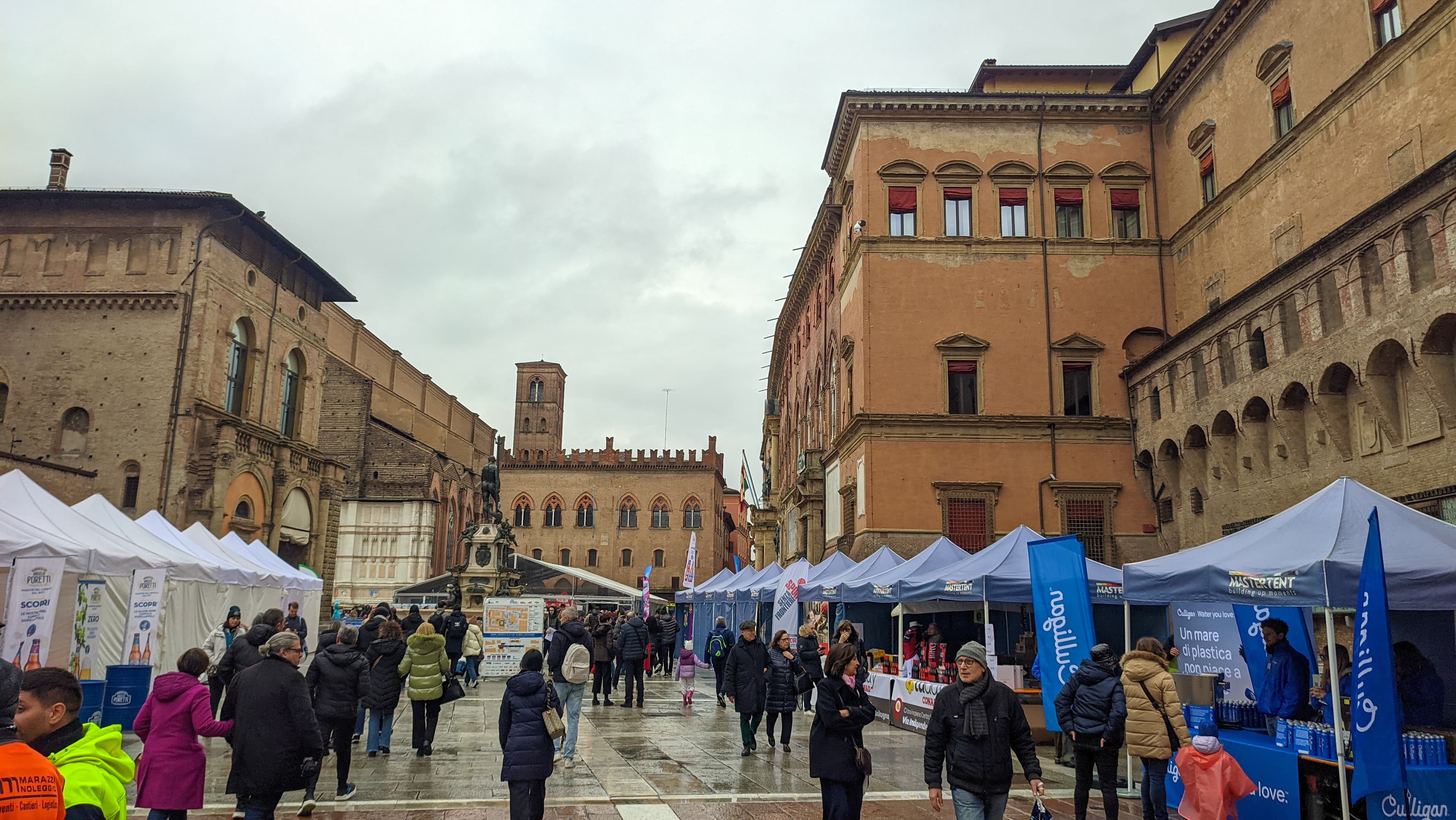 The Termal Bologna Marathon race expo inside a historic Bologna venue, with runners collecting bib numbers and browsing exhibitor stands
