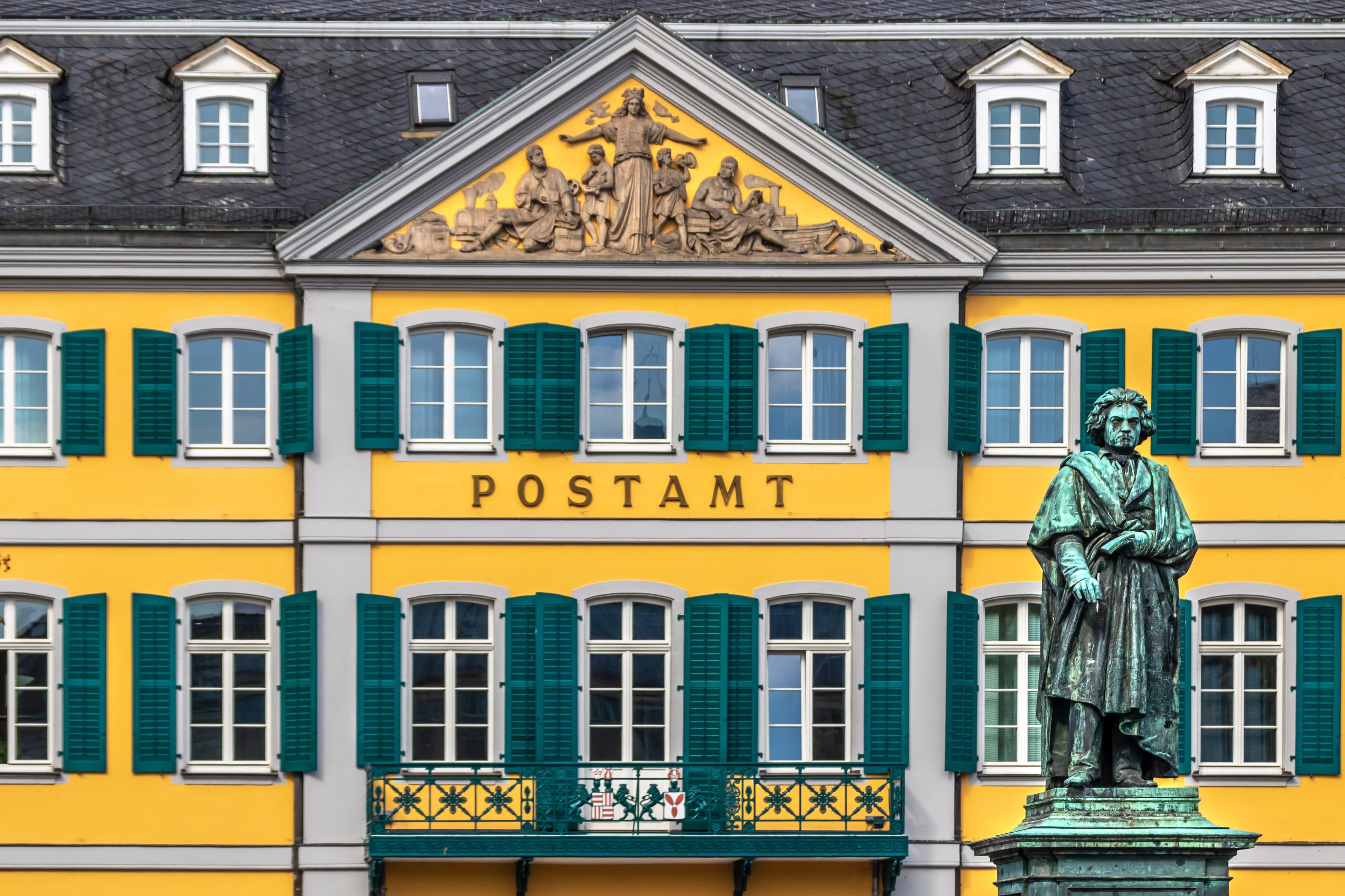 The bronze Beethoven monument on Bonn's Münsterplatz, standing in front of the yellow former Postamt building with its green shutters, a few minutes' walk from the marathon finish on the Markt