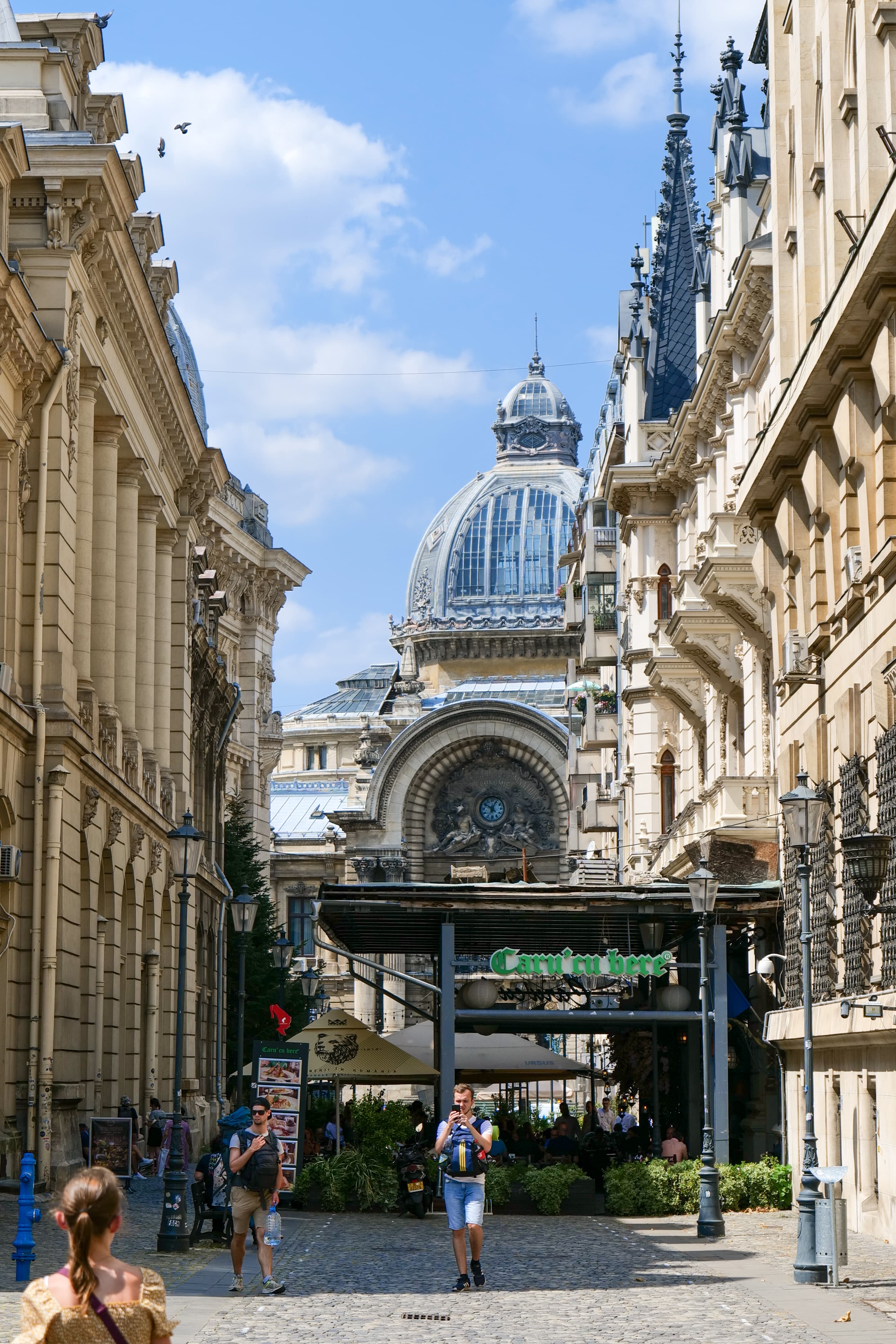 A cobbled Lipscani street in Bucharest's Old Town, with the CEC Palace dome visible above the rooftops