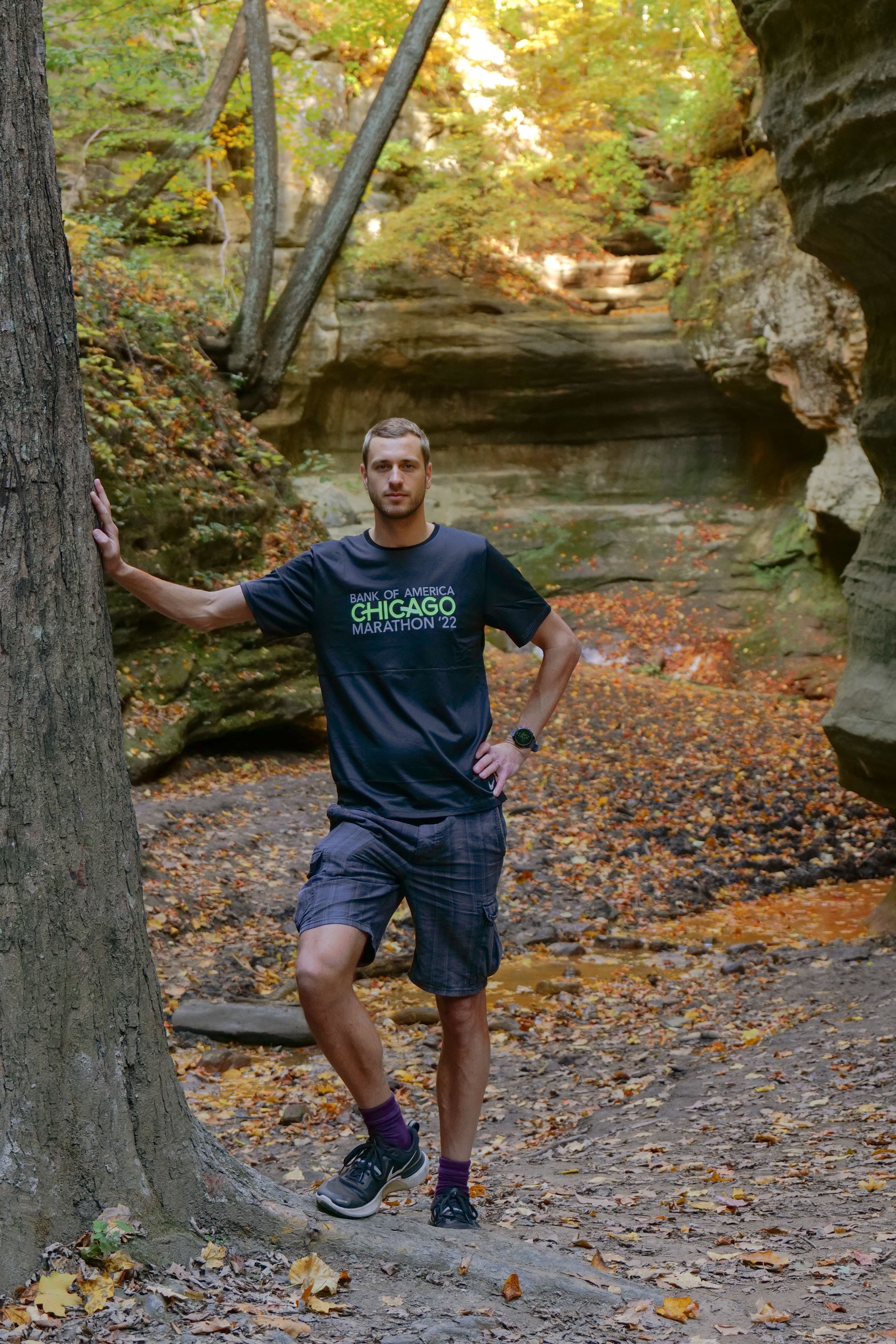 A runner wearing a Bank of America Chicago Marathon finisher's t-shirt standing in the narrow sandstone canyon at Matthiessen State Park, surrounded by fallen autumn leaves, two days after race day