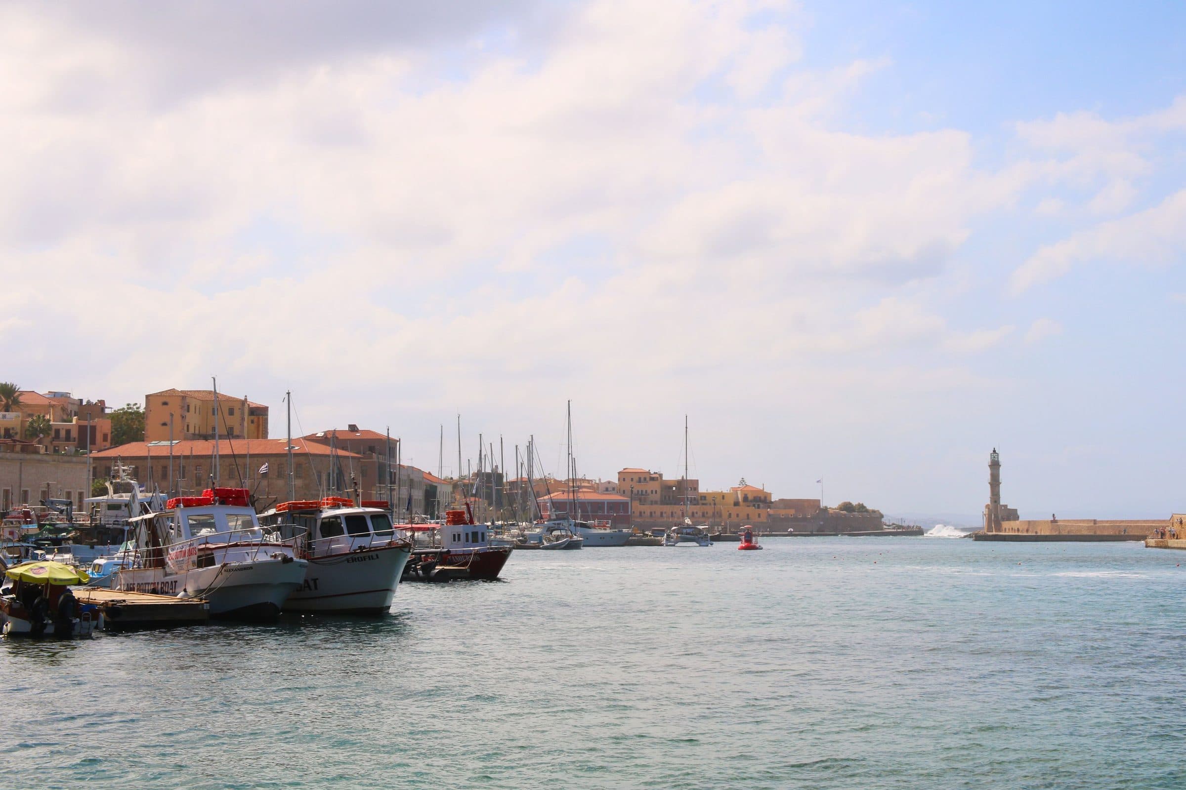 The Venetian harbour at Chania, Crete, with moored boats, the old town waterfront and the lighthouse at the harbour mouth
