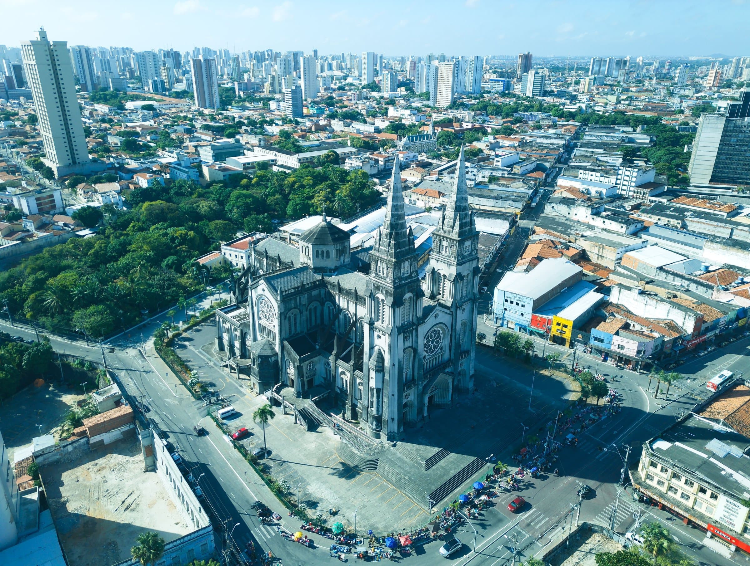 Aerial view of the twin-spired neo-Gothic cathedral in central Fortaleza, with tower blocks stretching away under a blue sky