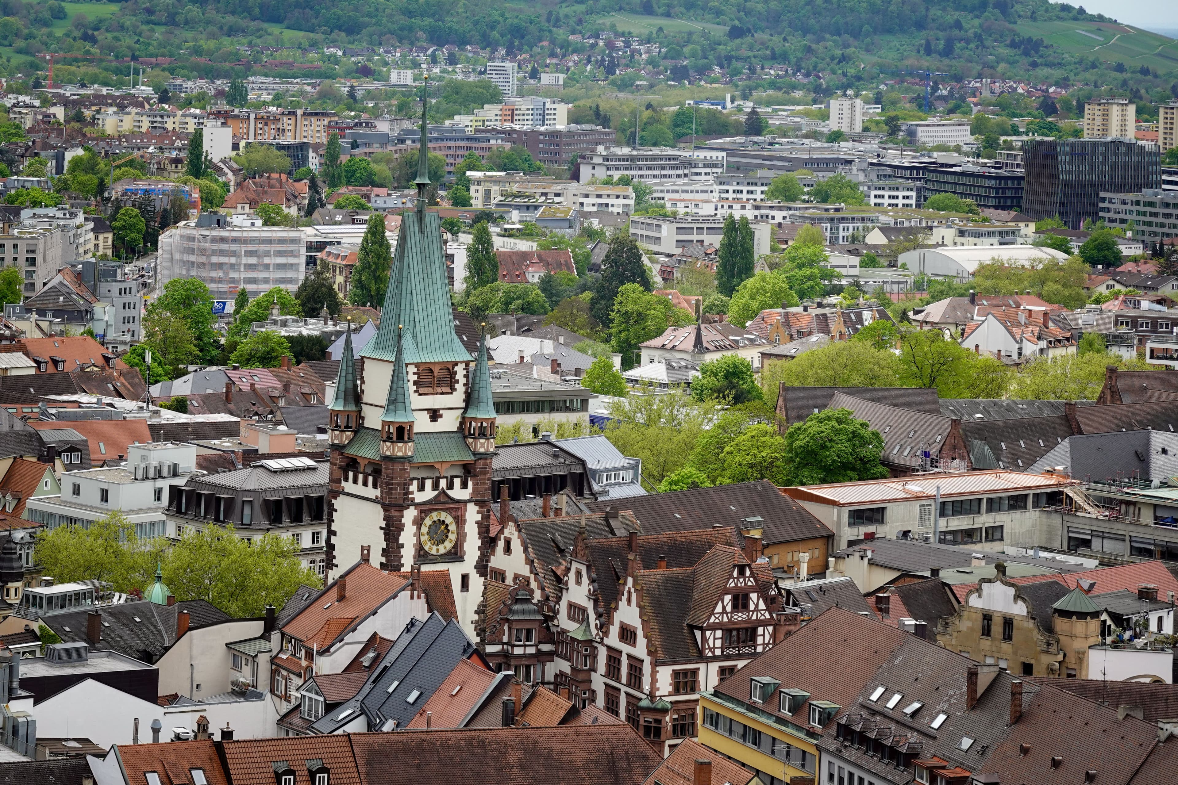 The Martinstor gate tower rising above the tiled roofs of Freiburg's Altstadt, with the western hills behind. The marathon runs through this old town on both laps.
