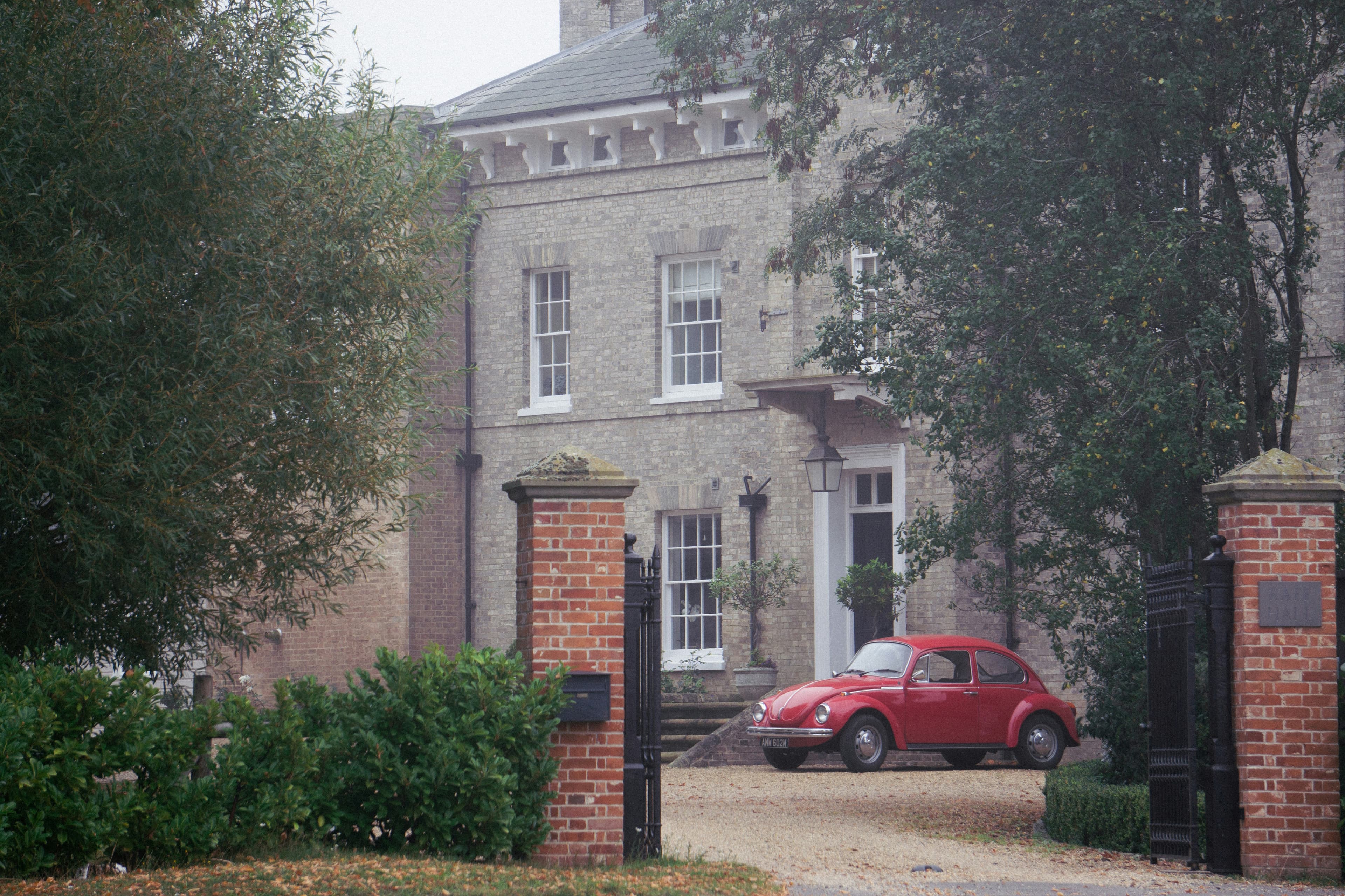 A Georgian brick house with a vintage red Volkswagen Beetle parked in the driveway, North Essex countryside near the Halstead & Essex Marathon route