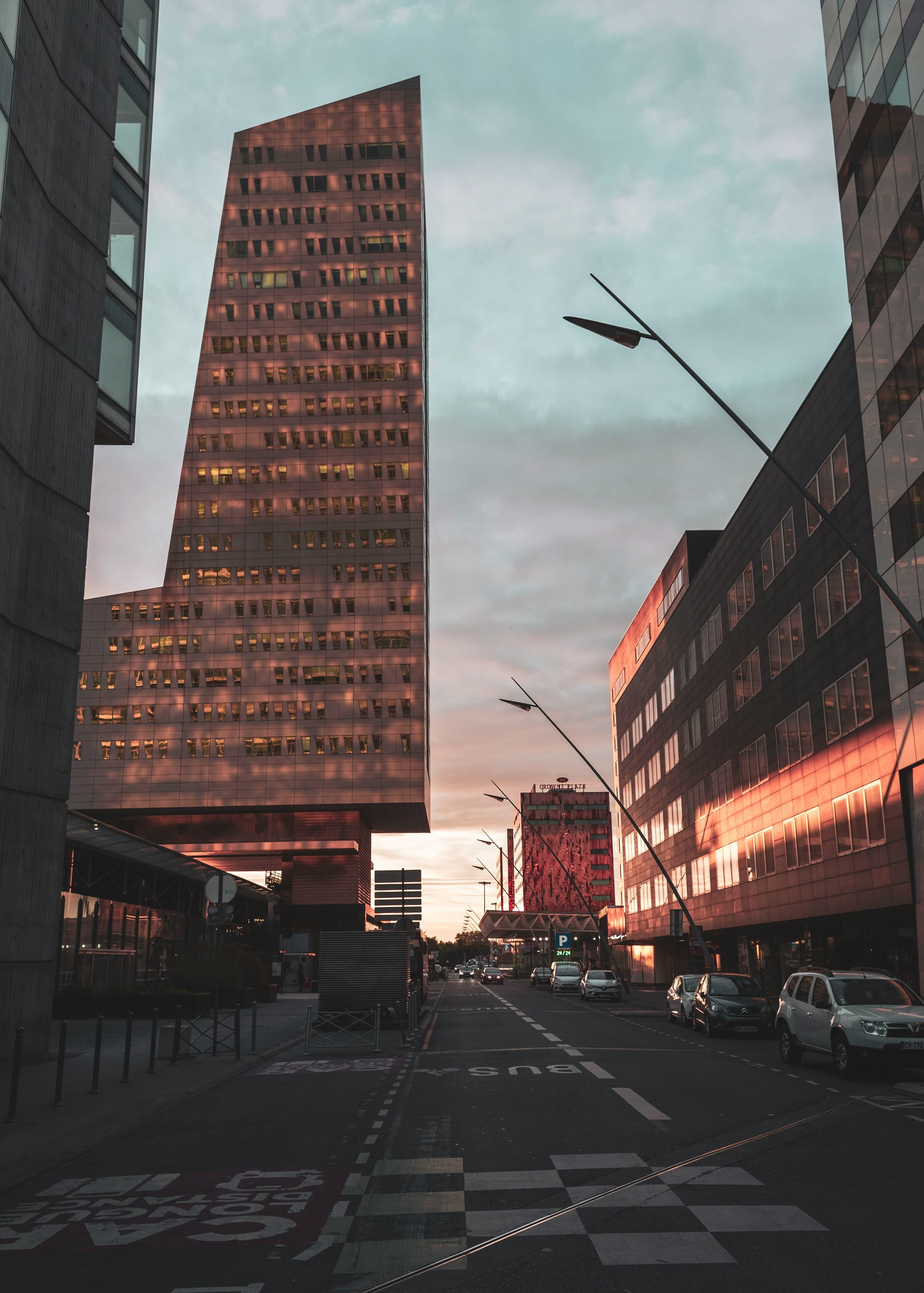 The Tour de Lille office tower in the Euralille business district at sunset, with the red facade of the Crowne Plaza hotel at the end of the street. The marathon course passes Lille Flandres station nearby at 2.3 km and 37.9 km.