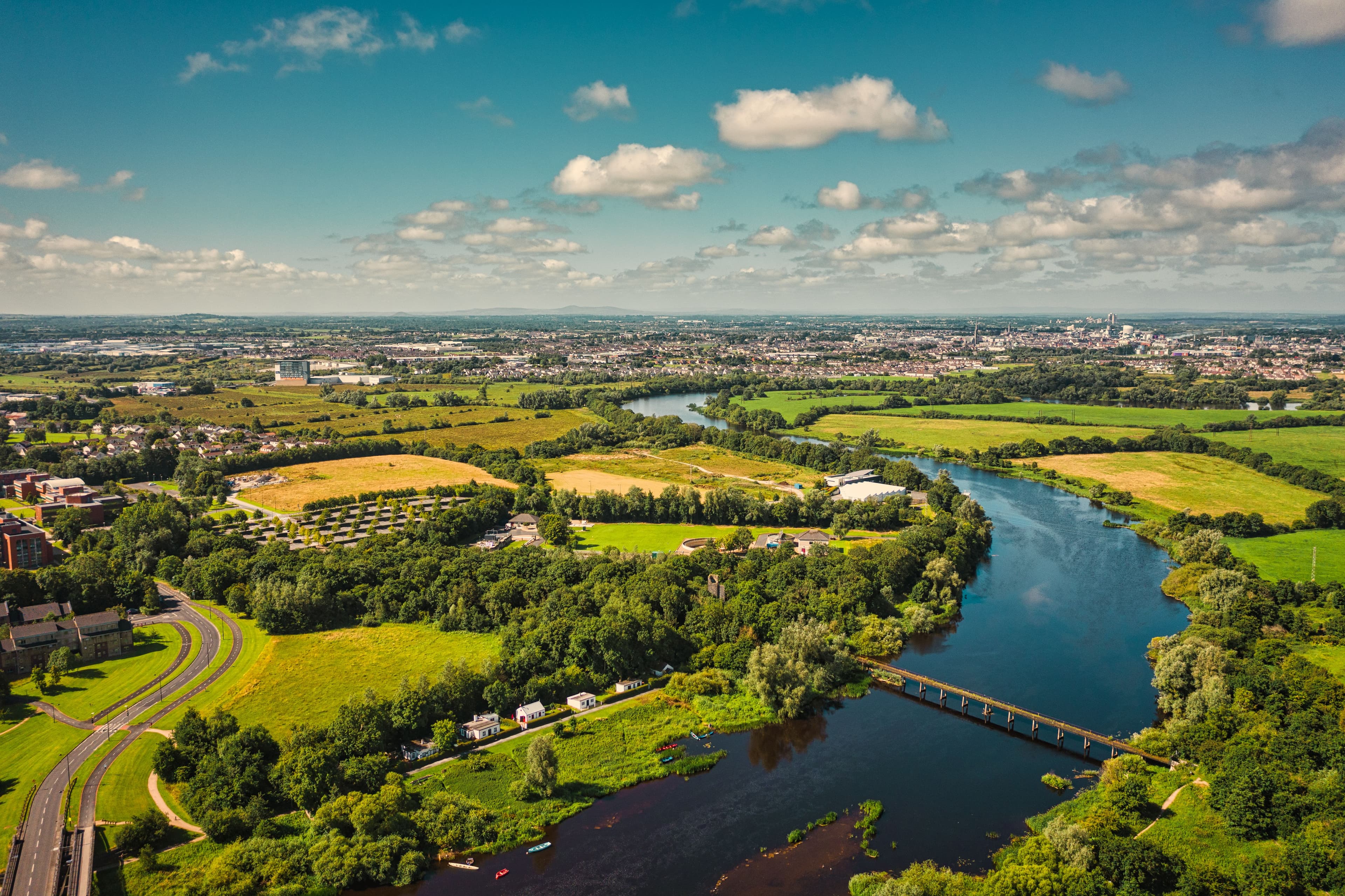 Aerial view of the University of Limerick campus along the River Shannon, with the pedestrian Living Bridge visible, part of the marathon route