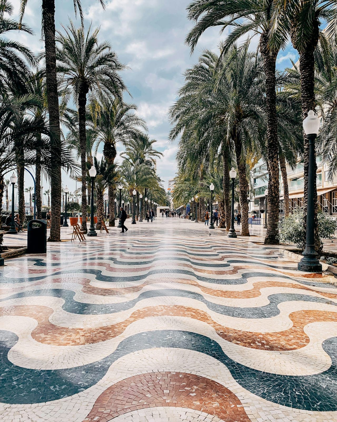 The wave-pattern mosaic pavement of the Explanada de España in Alicante under an avenue of palm trees, which the marathon runs at km 39.7