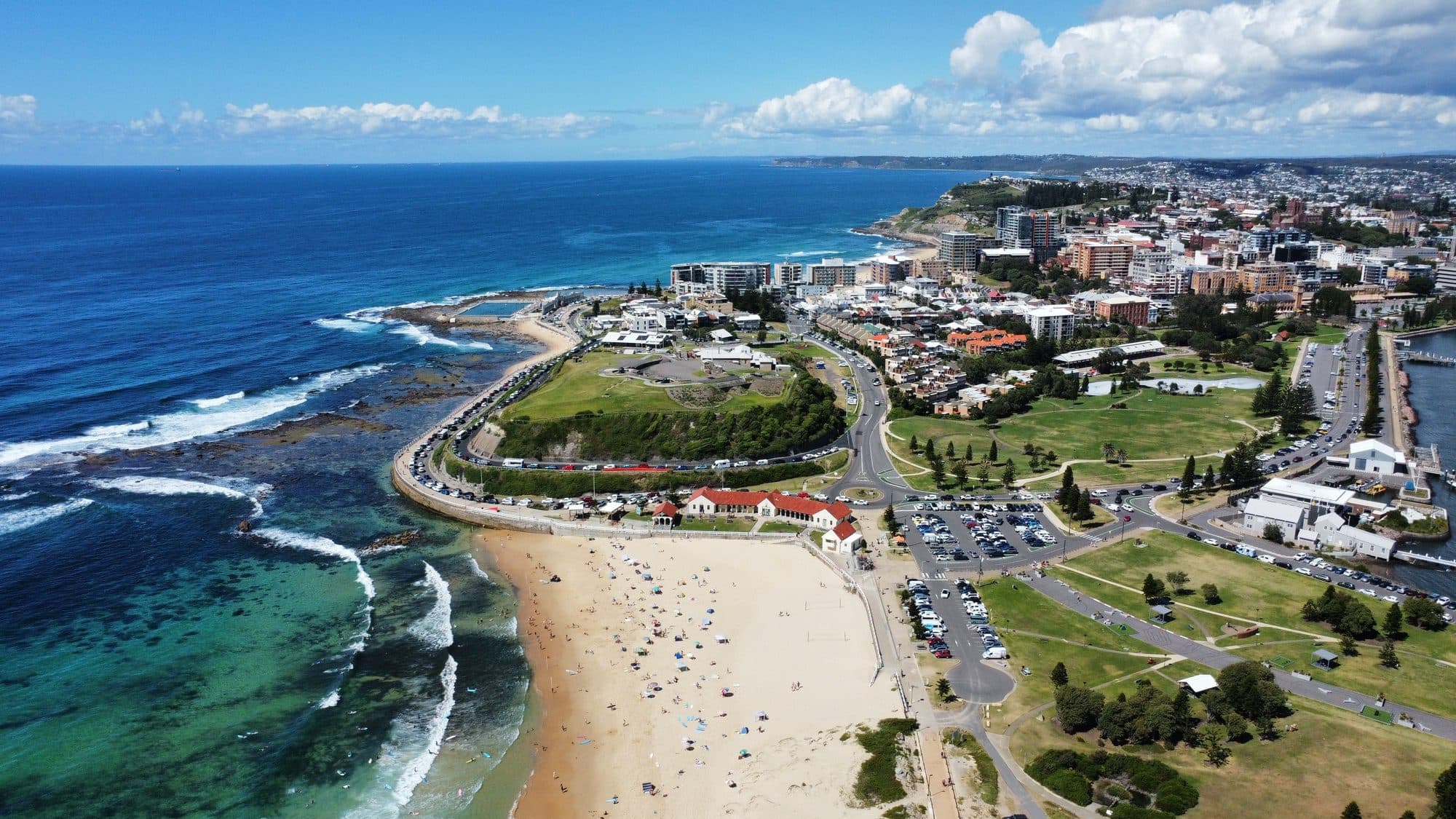 Aerial view of Newcastle Beach, the Bogey Hole coast, Fort Scratchley and the green lawns of Foreshore Park beside the harbour entrance in New South Wales