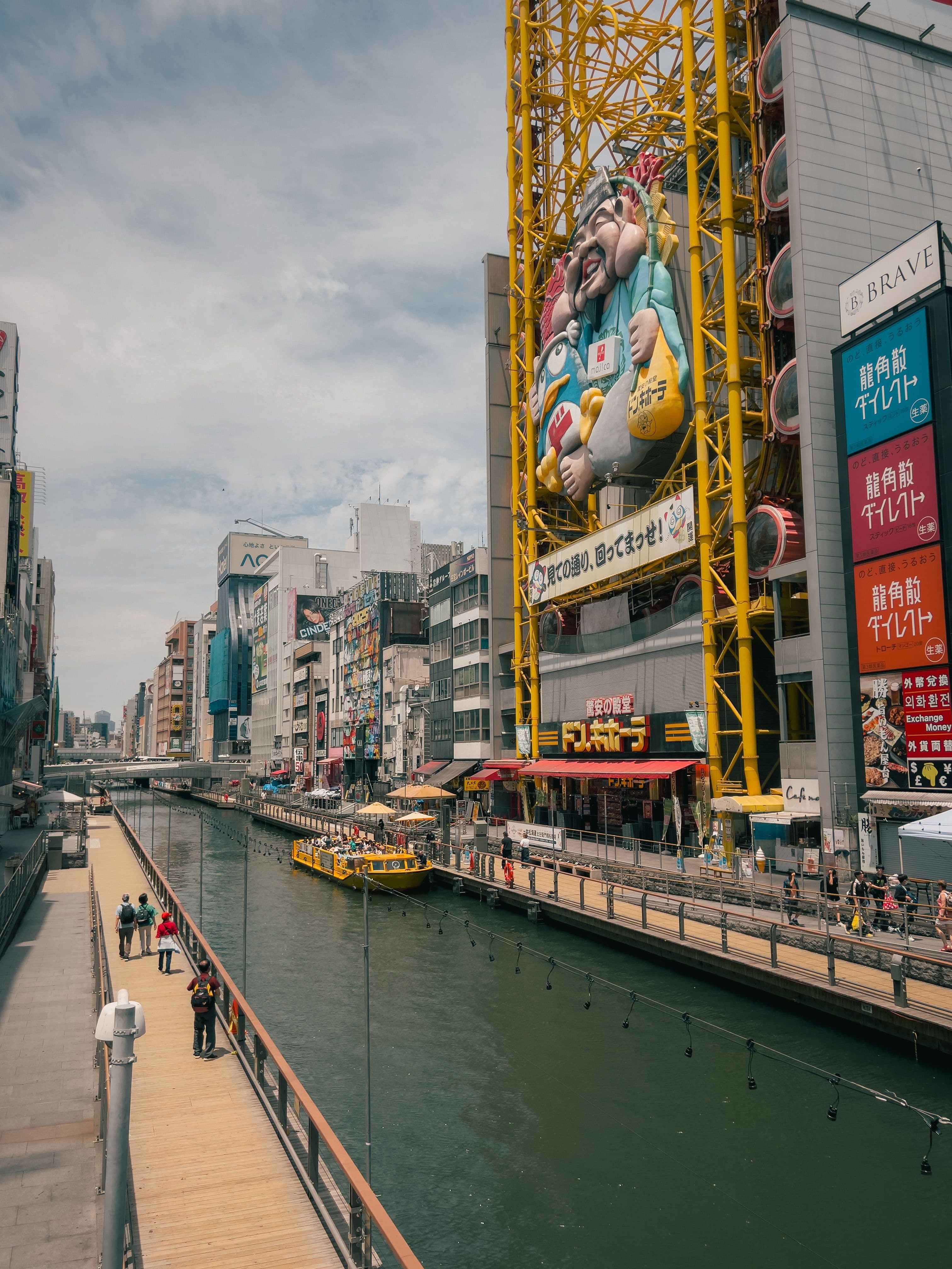 A tourist boat on the Dotonbori canal in Osaka, beneath the giant Kuidaore Taro and Don Quijote signage