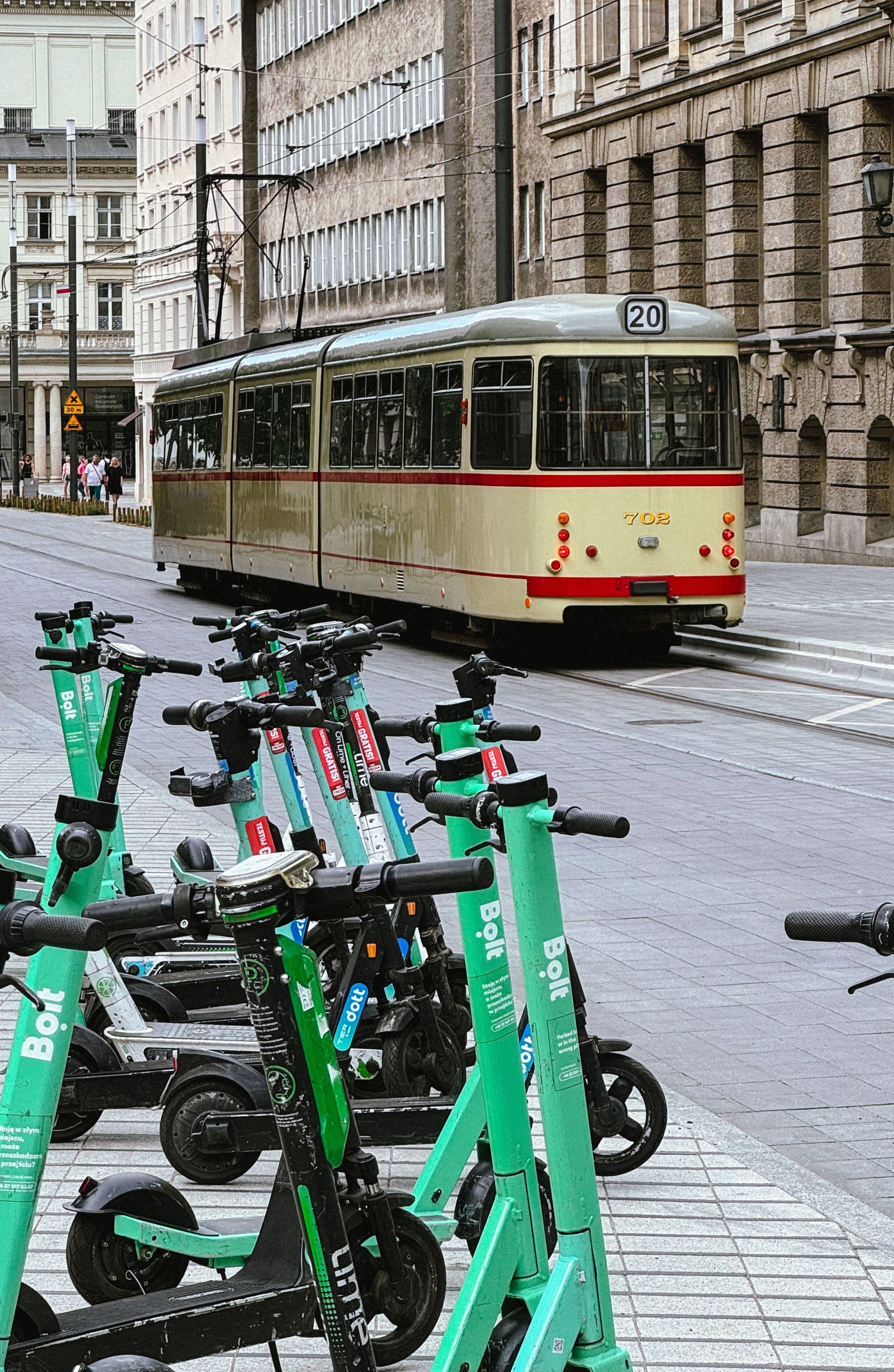 A tram passing through central Poznań, with parked e-scooters in the foreground
