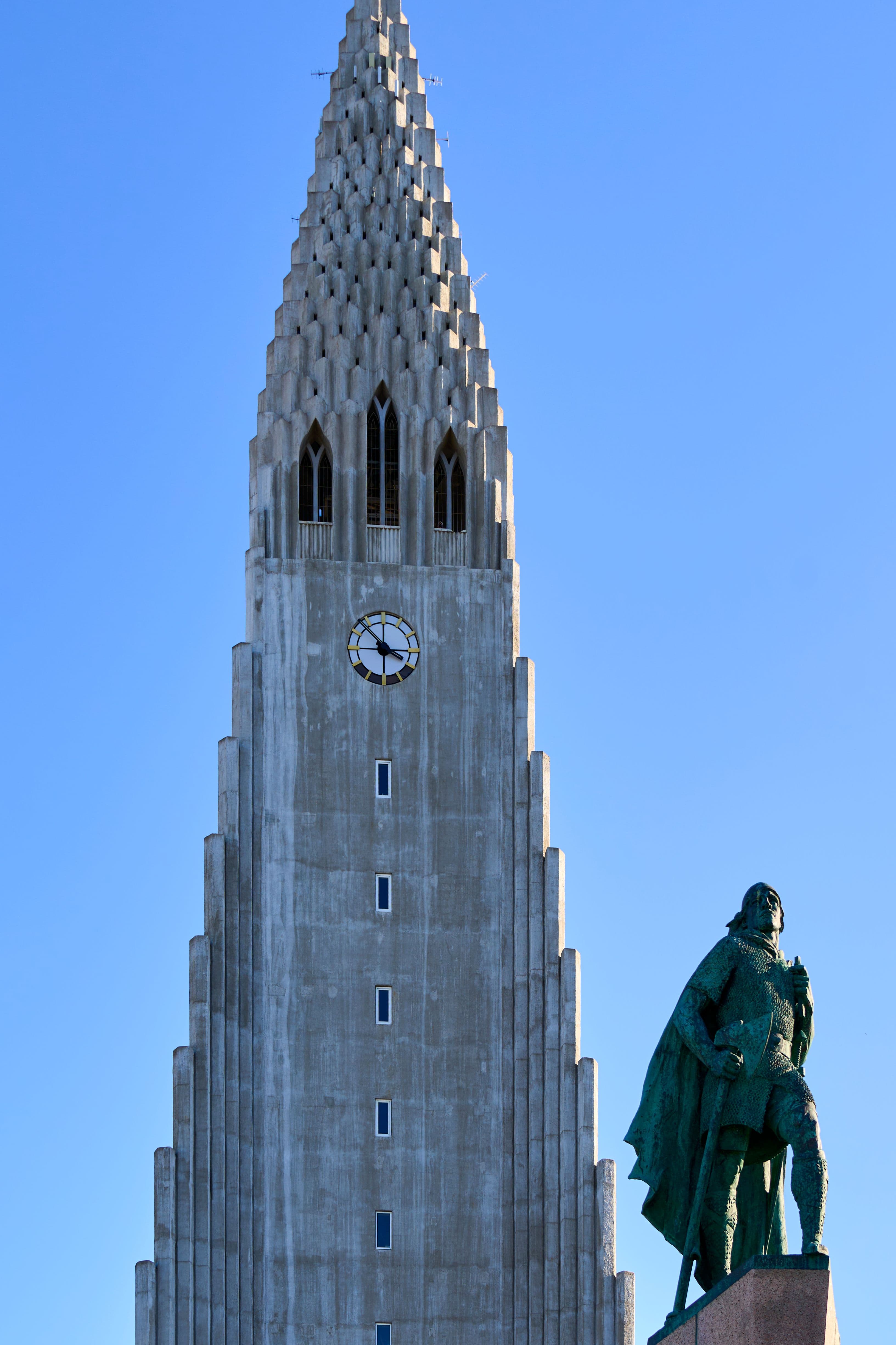Hallgrímskirkja church tower against a clear blue sky, with the Leif Erikson statue in the foreground