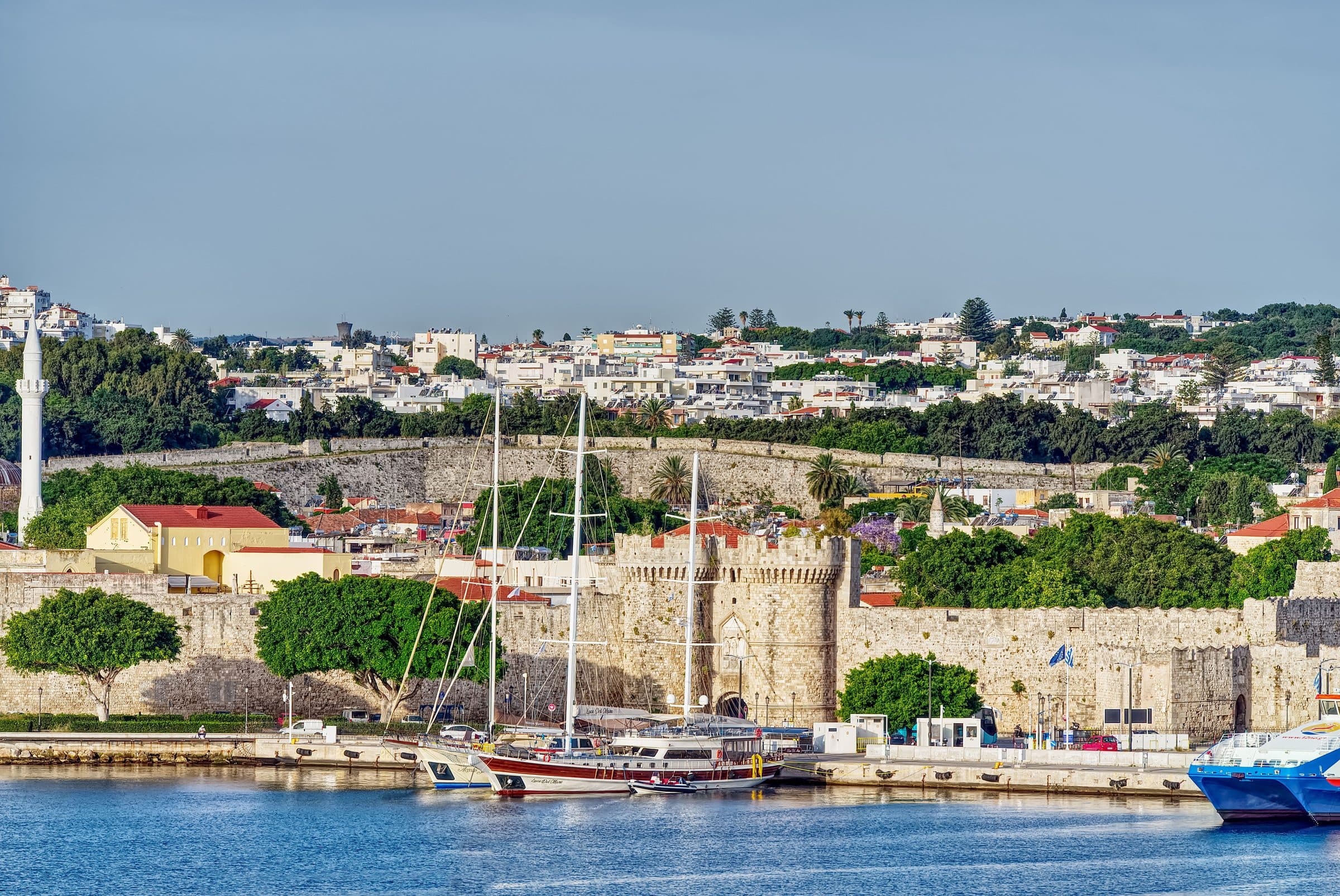 The sea wall and Marie Tower of the Medieval City of Rhodes seen from the harbour at Mandraki, with moored yachts in front of the stone ramparts