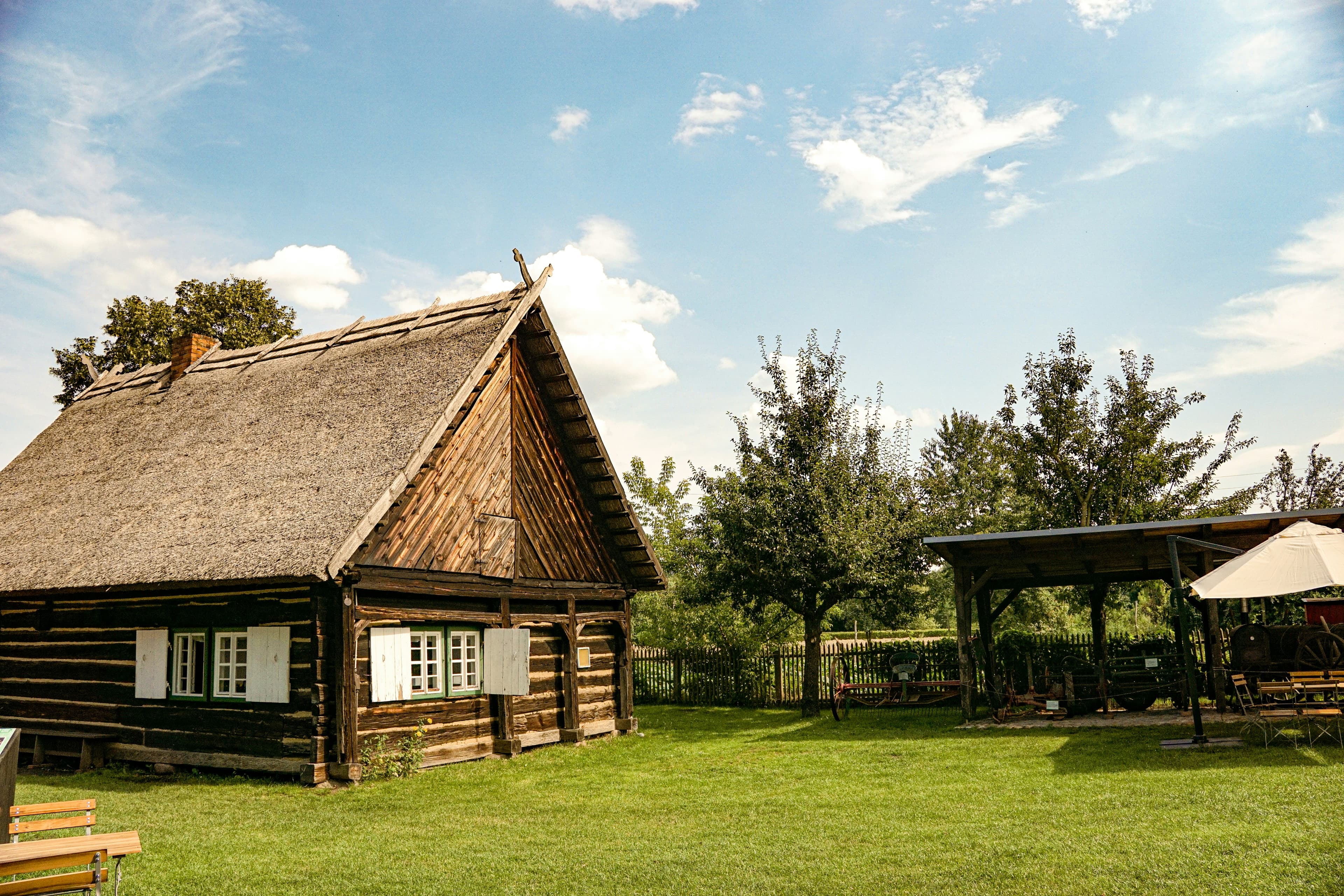 A traditional thatched Spreewald log house at Lehde, with orchard trees and open grass around it. The marathon runs through this biosphere-reserve landscape of flat paths, meadows and waterways.
