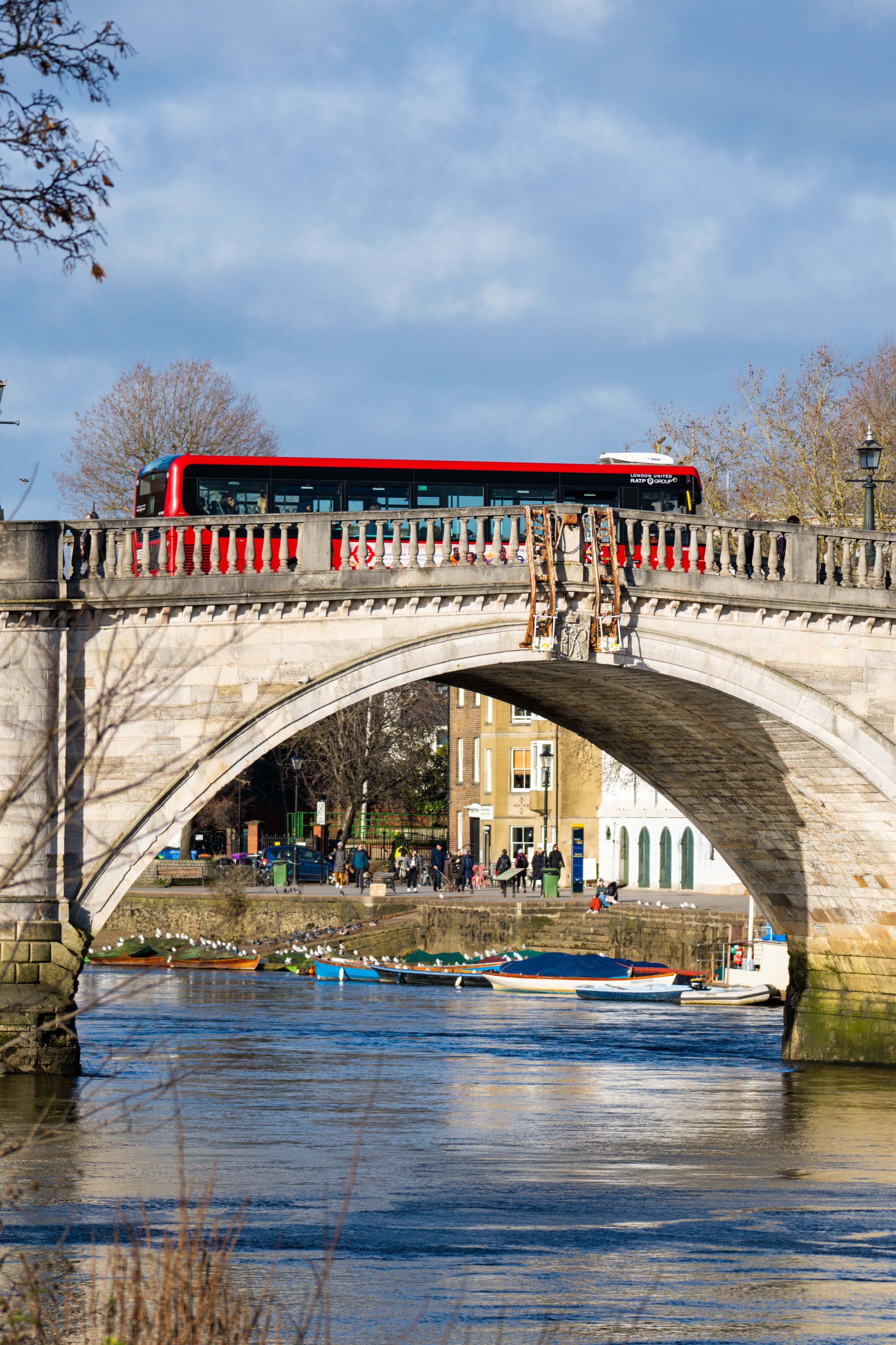 A road bridge over the Thames near Richmond, with moored boats on the riverbank below