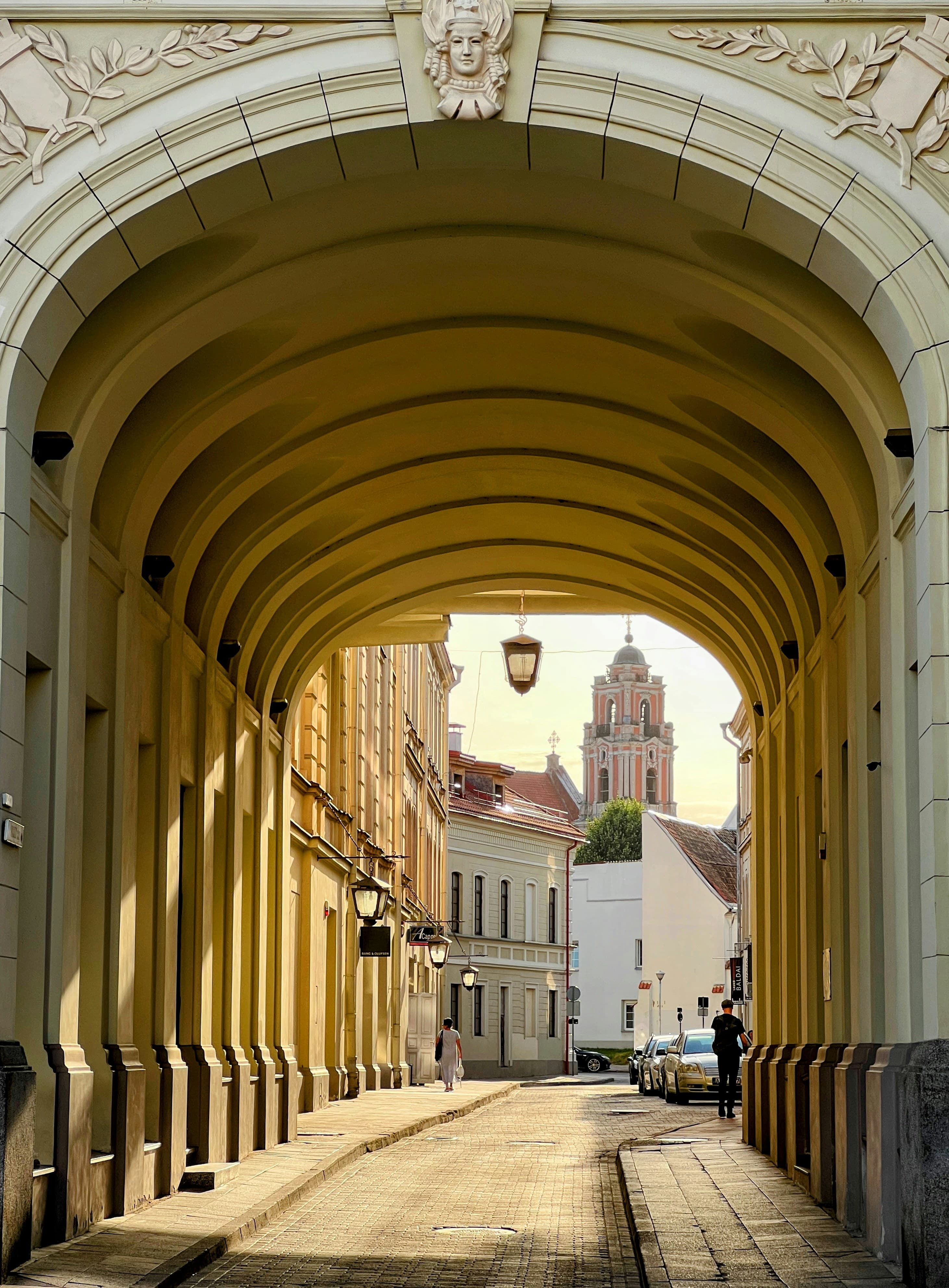 An archway in Vilnius's Old Town with a Baroque church tower visible beyond, part of the marathon course