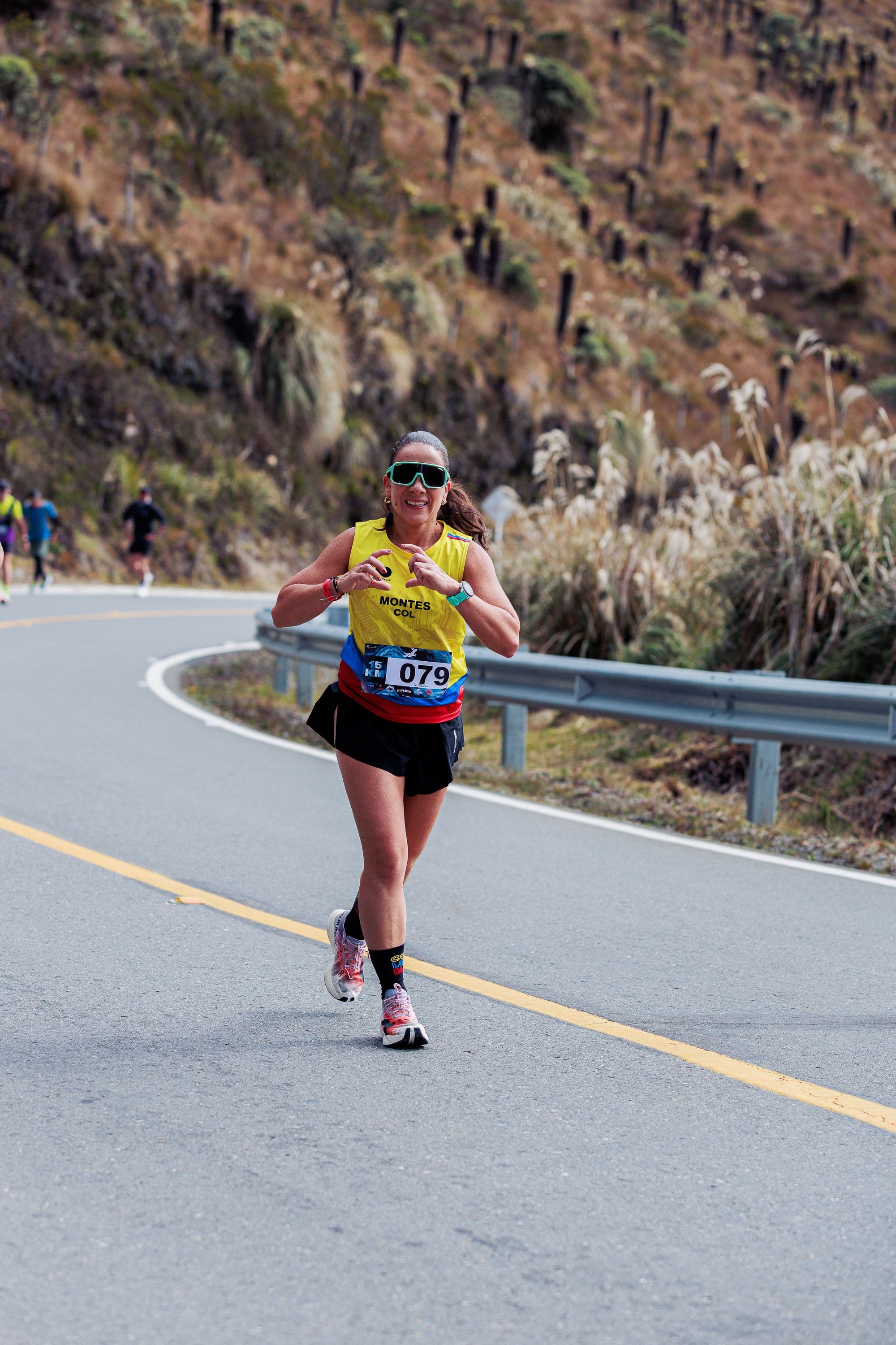 A runner on a hilly road marathon course at altitude, showing significant elevation gain ahead.